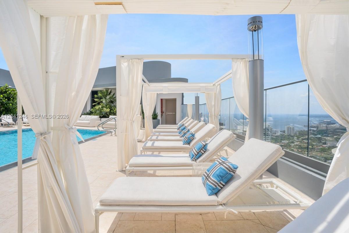 A rooftop pool deck features multiple lounge chairs under white fabric cabanas overlooking the ocean — 1000 Brickell Plz # 2101, Miami FL 33131, MIAMI, FL