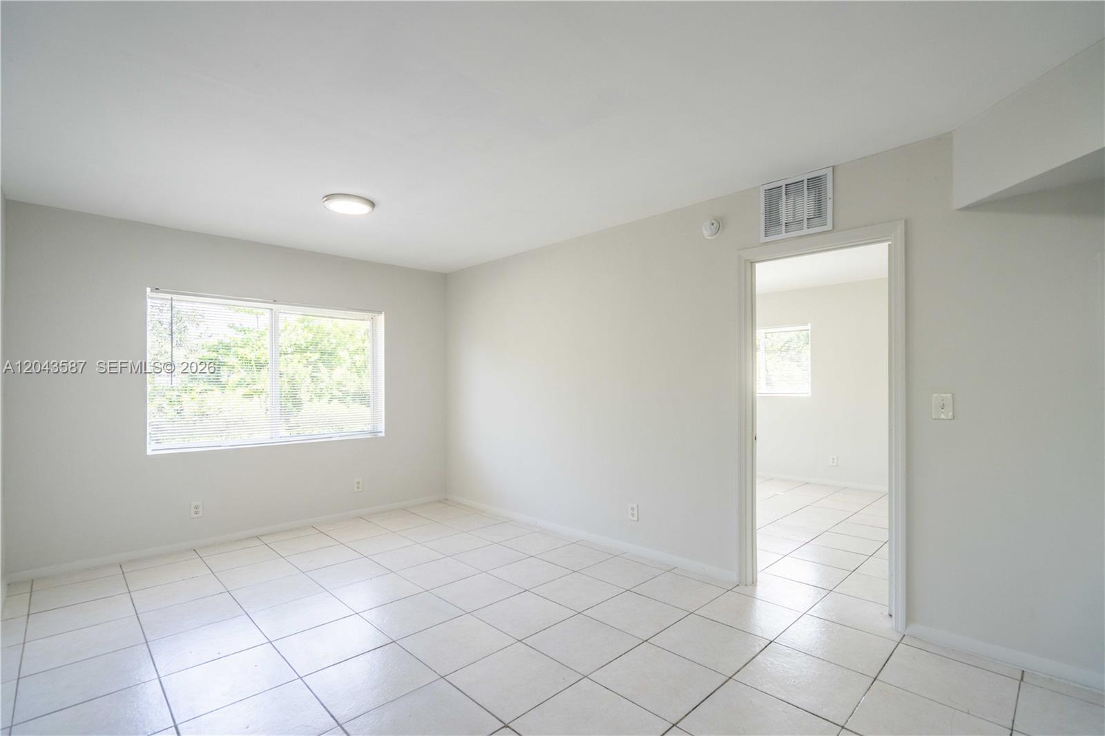 An empty room with white tile floors, a window, and a doorway to another room — 666 NE 80th St # 6, Miami FL 33138, MIAMI, FL