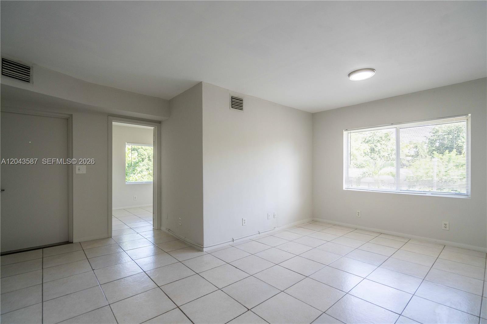 An empty room with white walls, tiled floors, and a window with blinds — 666 NE 80th St # 6, Miami FL 33138, MIAMI, FL