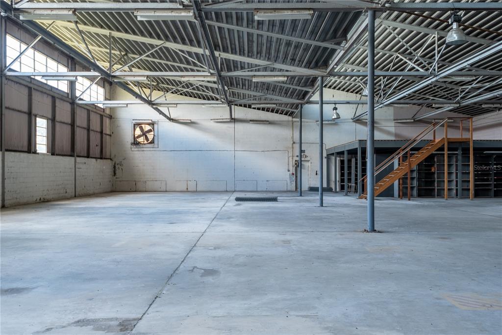 An expansive industrial warehouse space features concrete floors, exposed steel trusses, and a mezzanine level — 5000 SE HWY 31 UNIT W, ARCADIA, FL