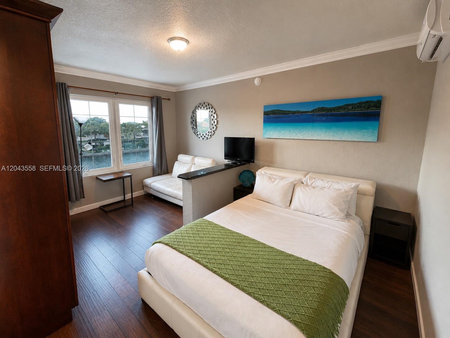 A bedroom features a bed, a small sofa, a television, and a view of water — 3025 Indian Creek Dr # 320, Miami Beach FL 33140, MIAMI BEACH, FL