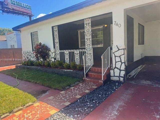 A single-story house features a covered porch with decorative metal railings and stone accents — 740 NW 42nd St, Miami FL 33127, MIAMI, FL