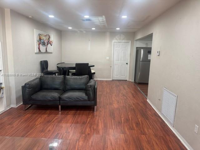 A living room with wood-look flooring, a dark leather sofa, and an adjacent dining area — 740 NW 42nd St, Miami FL 33127, MIAMI, FL