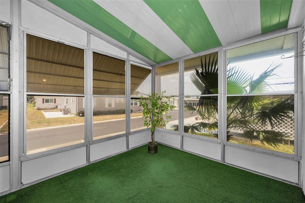 A screened-in porch features green artificial turf flooring and a striped green and white ceiling — 39820 US HIGHWAY 19 N UNIT 153, TARPON SPRINGS, FL