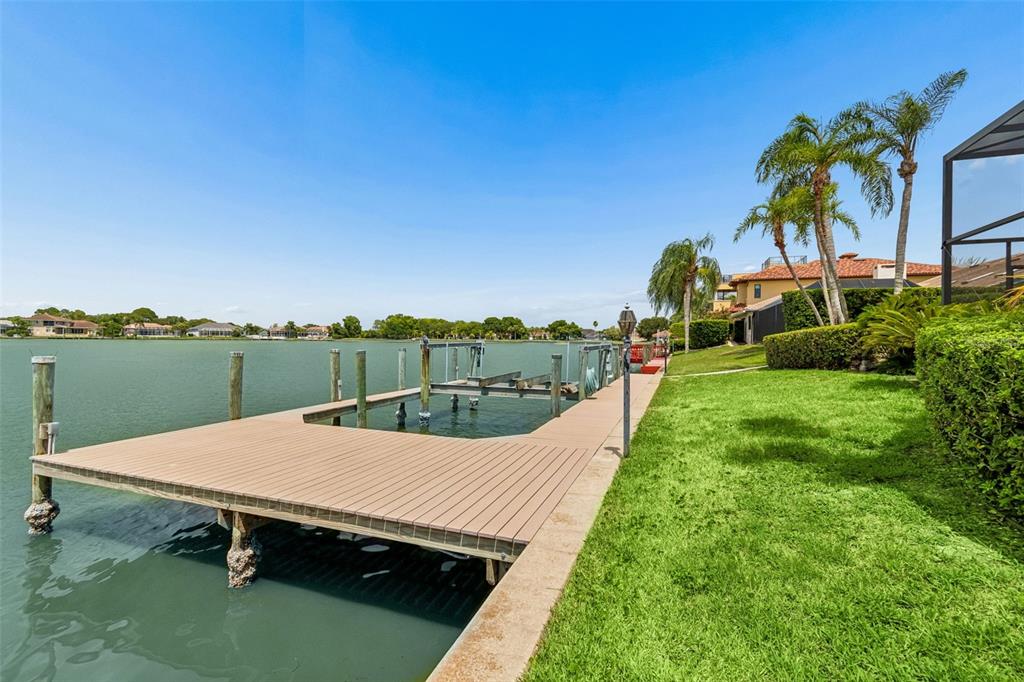 An aerial view shows a tan house with a tiled roof, garage, and waterfront backyard — 9815 BAY ISLAND DRIVE, TAMPA, FL