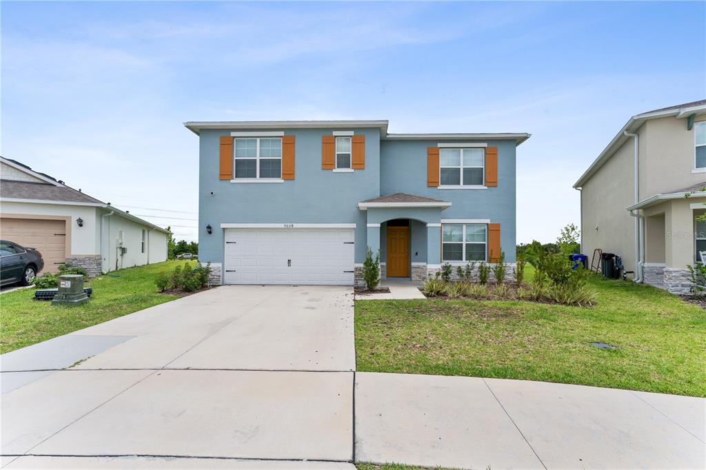 A two-story blue house with a white garage door, orange shutters, and a concrete driveway — 5038 FOXGLOVE CIRCLE, LAKELAND, FL