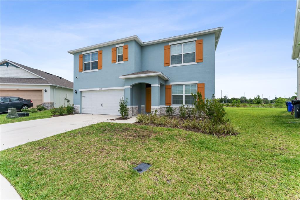 A two-story blue house with a two-car garage, stone accents, and orange shutters — 5038 FOXGLOVE CIRCLE, LAKELAND, FL