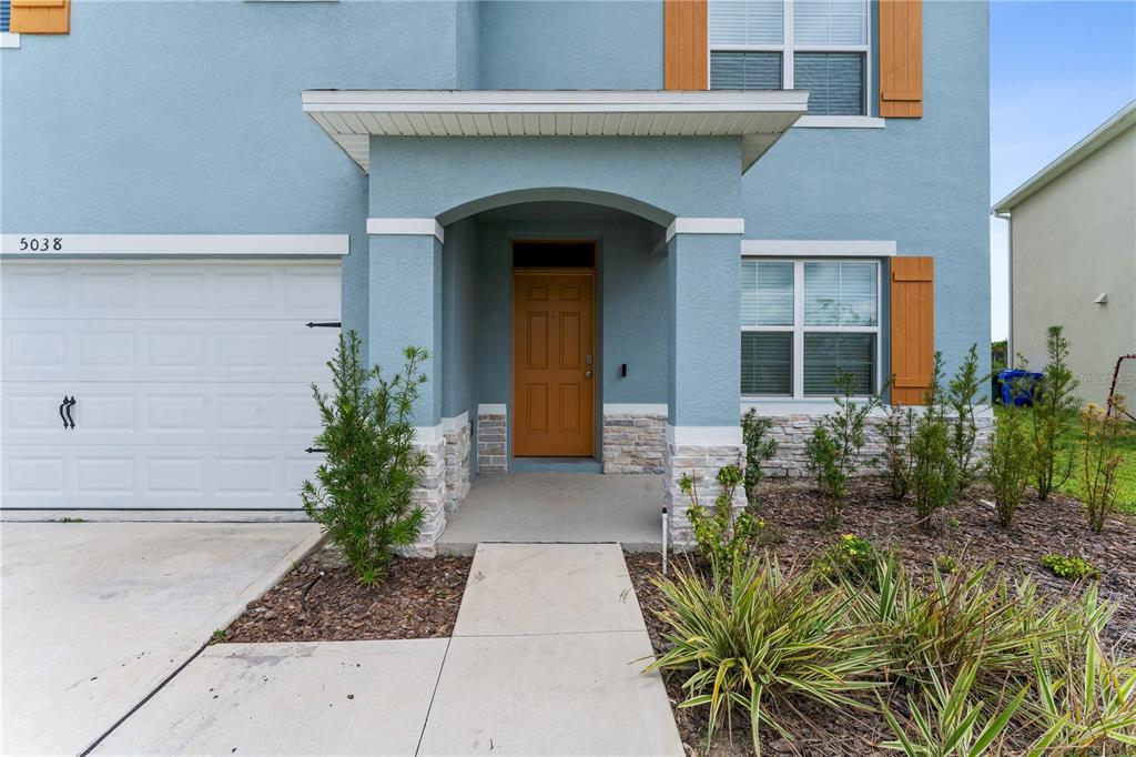 The exterior of a blue two-story house features a tan front door and stone accents — 5038 FOXGLOVE CIRCLE, LAKELAND, FL