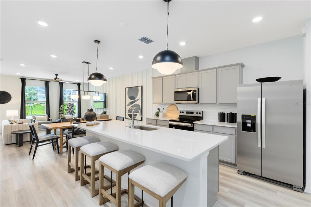 A modern kitchen with a white island, grey cabinets, and stainless steel appliances — 6262 SUNNY TIME AVENUE, WINTER GARDEN, FL