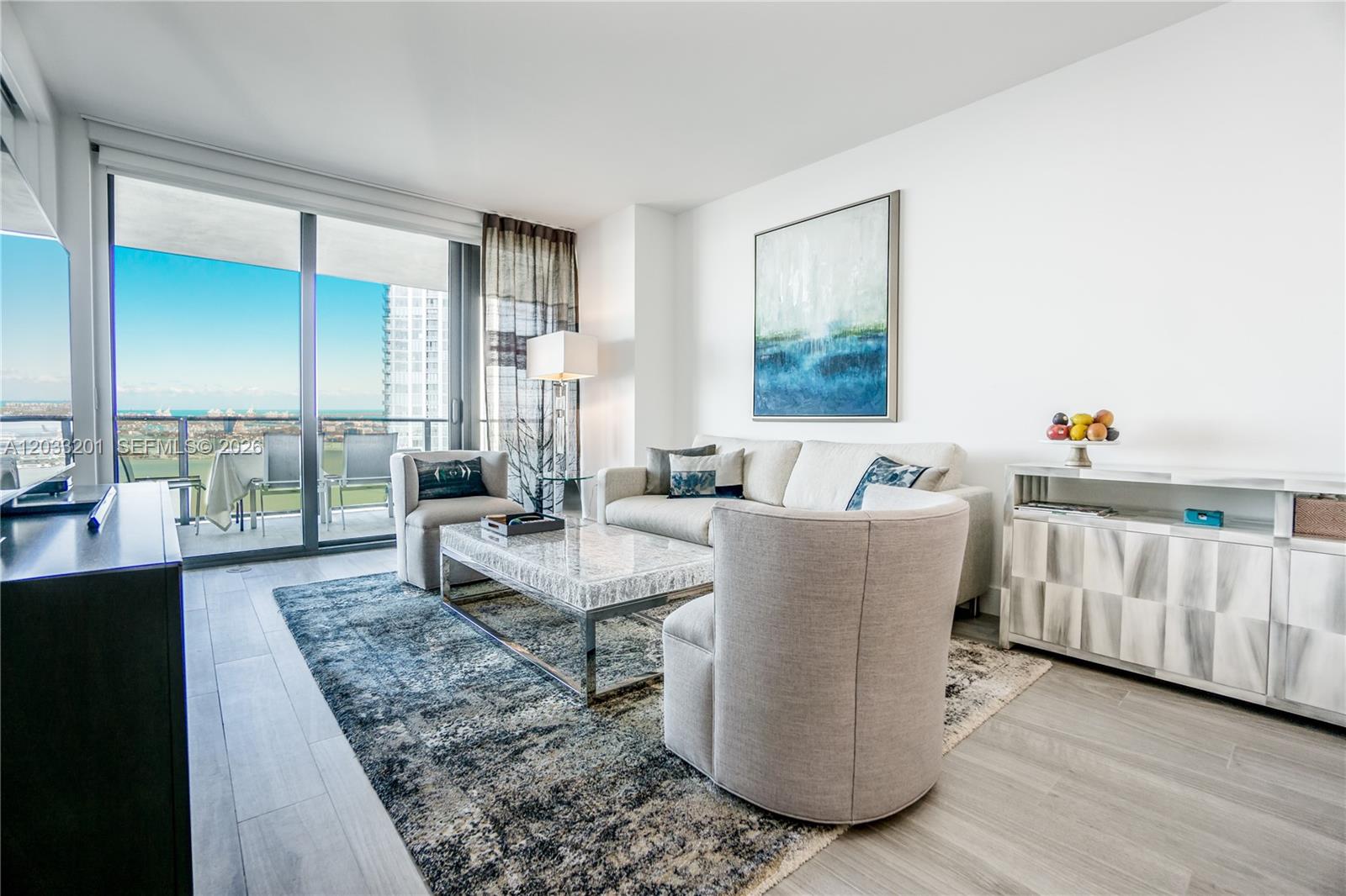 A modern living room features a sofa, armchairs, a coffee table, and a balcony view — 650 NE 32nd St # 3505, Miami FL 33137, MIAMI, FL