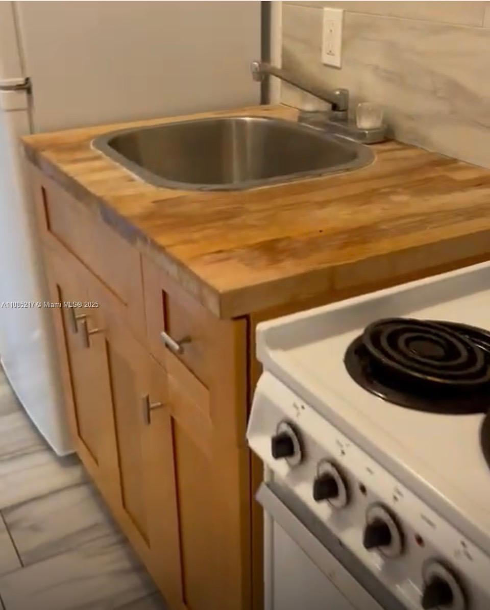 A small kitchen features a wooden countertop, a stainless steel sink, and a white stove — 506 18th St # B, West Palm Beach FL 33407, WEST PALM BEACH, FL