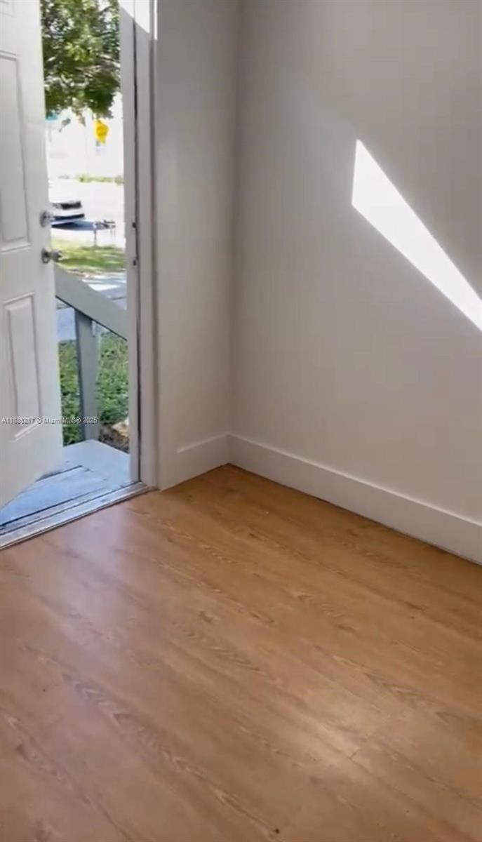 An interior view shows a room with light wood flooring, white walls, and an open door — 506 18th St # B, West Palm Beach FL 33407, WEST PALM BEACH, FL
