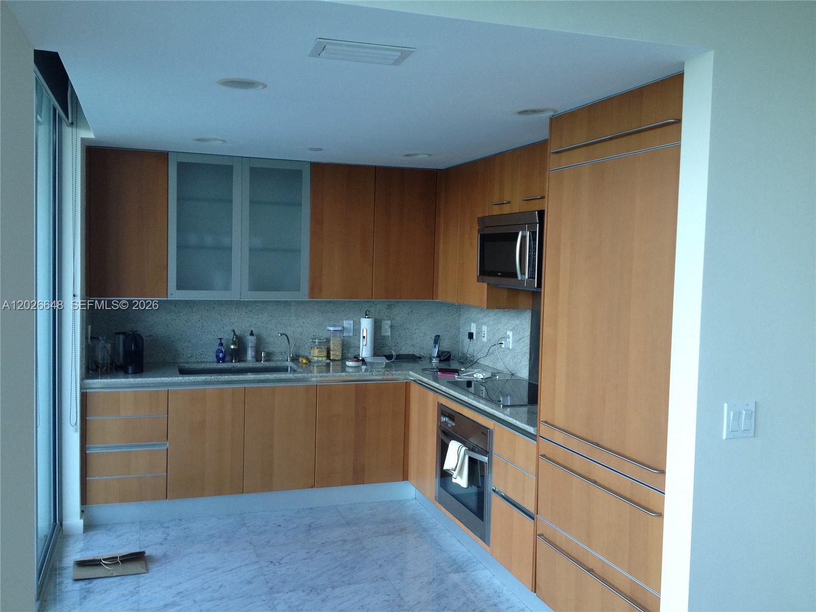 A kitchen features light wood cabinetry, granite countertops, stainless steel appliances, and marble flooring — 2627 S Bayshore Dr # 1208, Miami FL 33133, MIAMI, FL