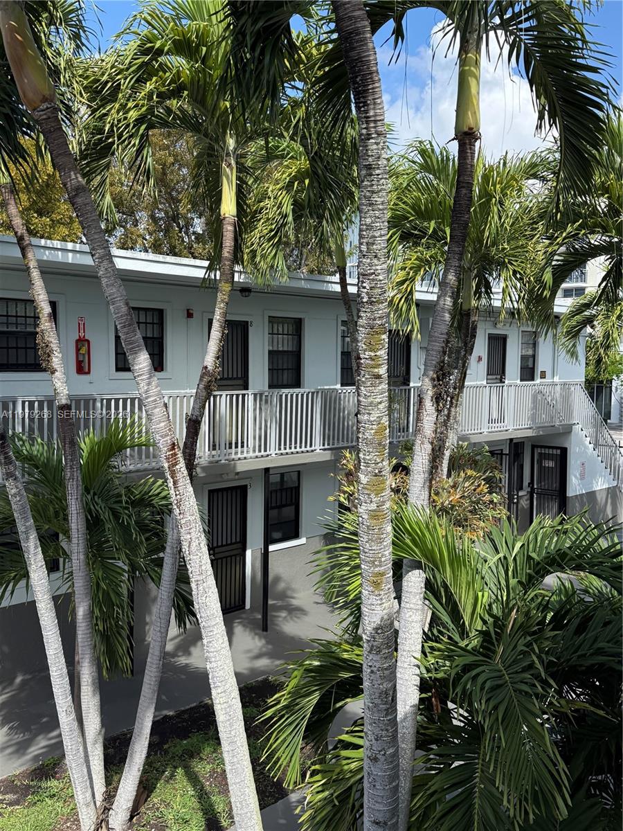 An exterior view of a two-story apartment building with palm trees and a metal balcony — 3616 Grand Ave # 7, Miami FL 33133, MIAMI, FL