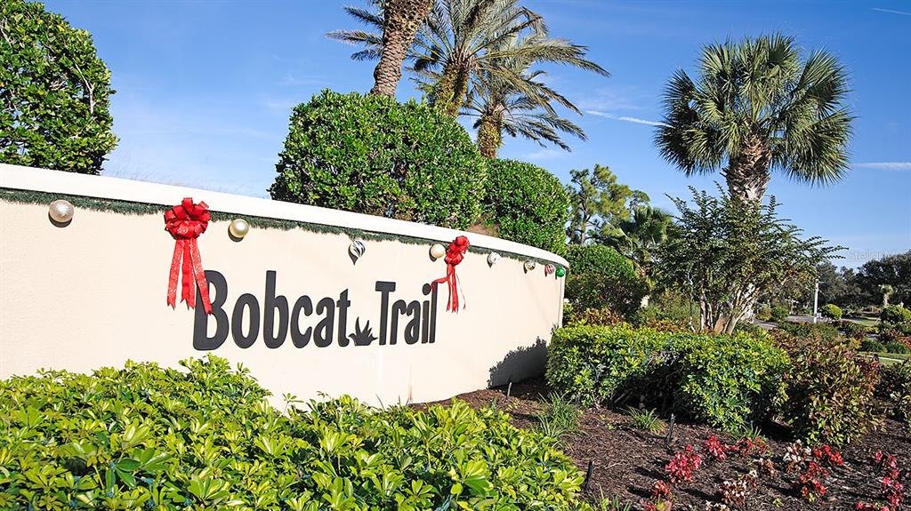A curved beige wall with the text Bobcat Trail is decorated with red bows and ornaments — 2775 ROYAL PALM DRIVE, NORTH PORT, FL