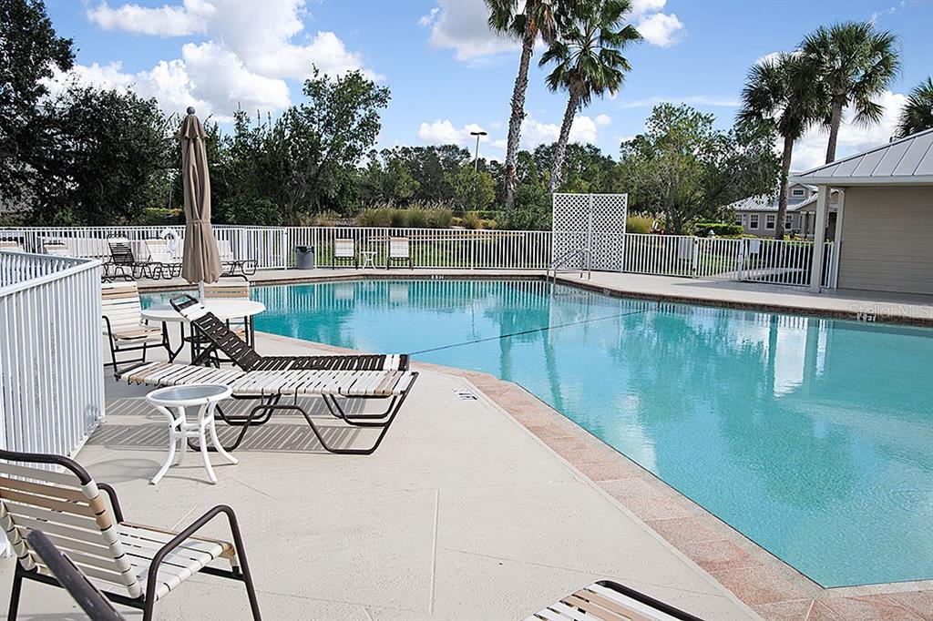 A swimming pool with lounge chairs and tables on a concrete deck under palm trees — 2775 ROYAL PALM DRIVE, NORTH PORT, FL