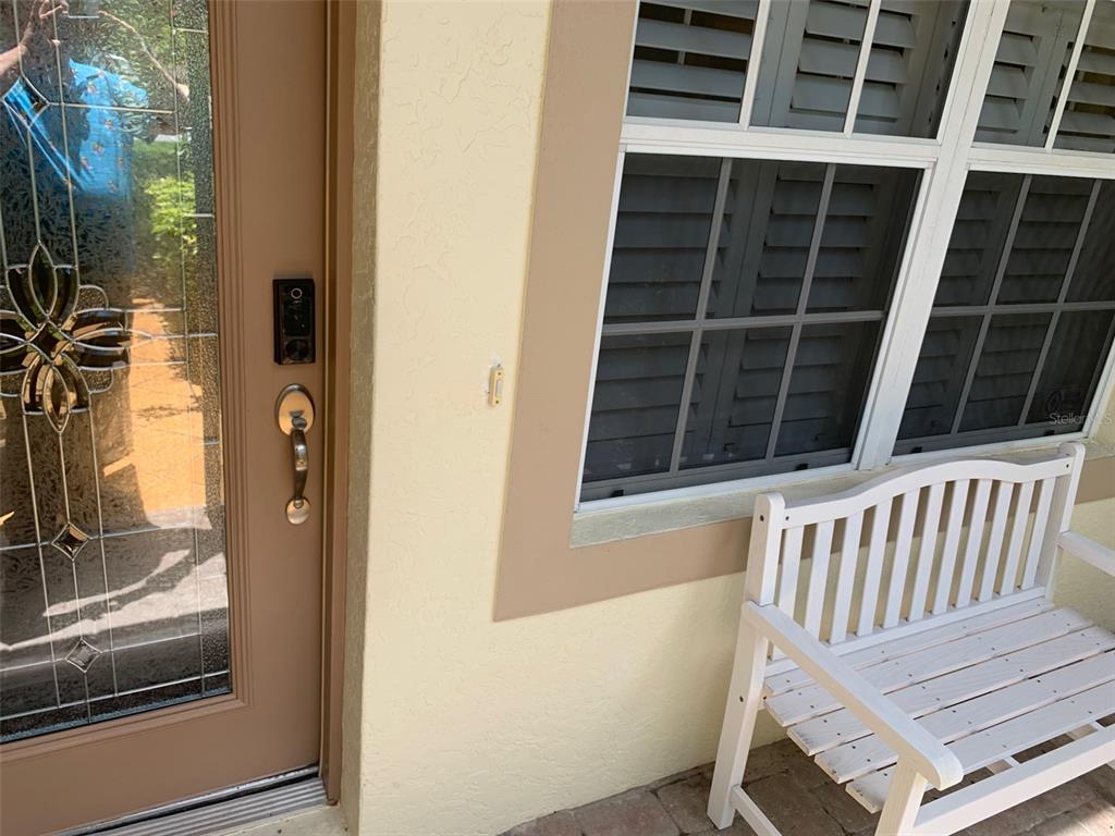 A front door with a decorative glass insert sits beside a window and white bench — 2775 ROYAL PALM DRIVE, NORTH PORT, FL