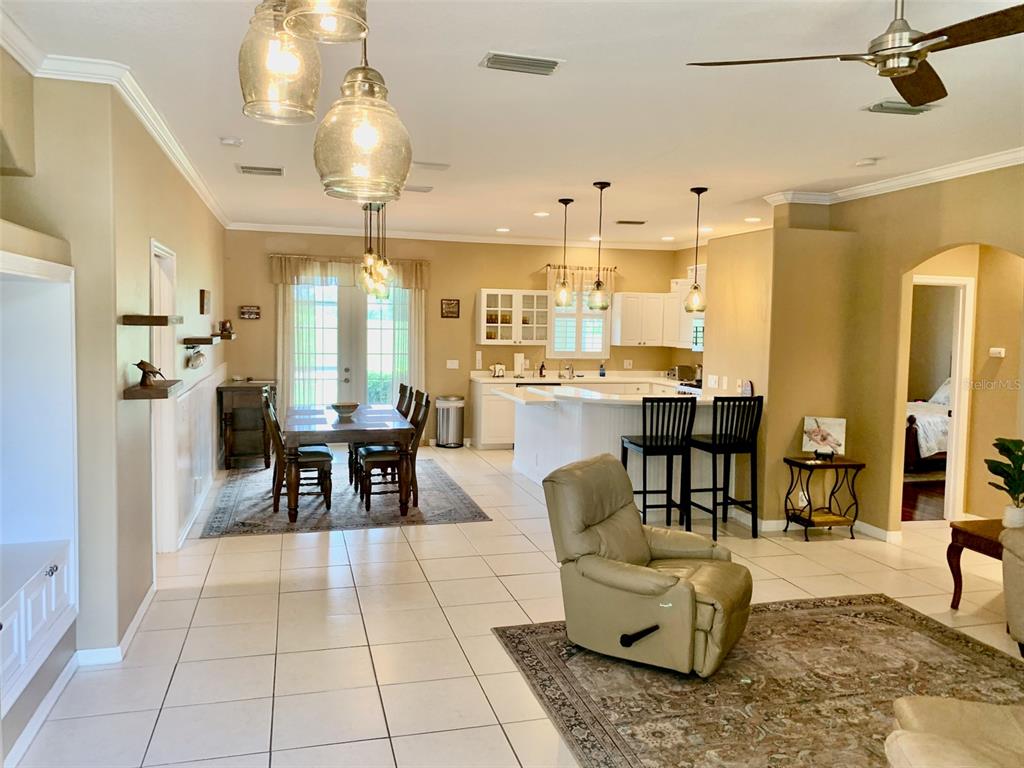 An open-concept living and dining area features tile flooring, a kitchen island, and pendant lighting — 2775 ROYAL PALM DRIVE, NORTH PORT, FL