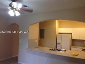 A kitchen with white cabinets and a breakfast bar opens into a living area — 5779 NW 116 AV # 101, Doral FL 33178, DORAL, FL