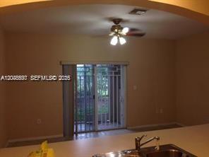 A kitchen counter overlooks a living area with a ceiling fan and sliding glass doors — 5779 NW 116 AV # 101, Doral FL 33178, DORAL, FL