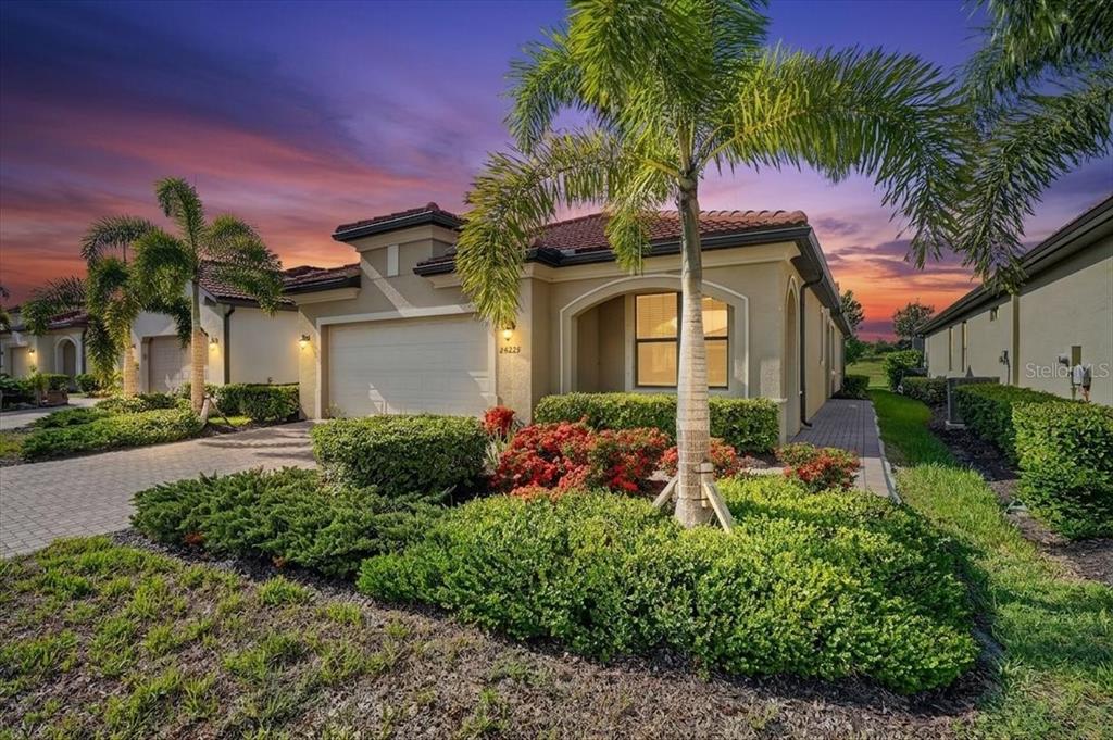A single-story stucco house with a tile roof, palm trees, and a paved driveway — 24229 SPARTINA DRIVE, VENICE, FL