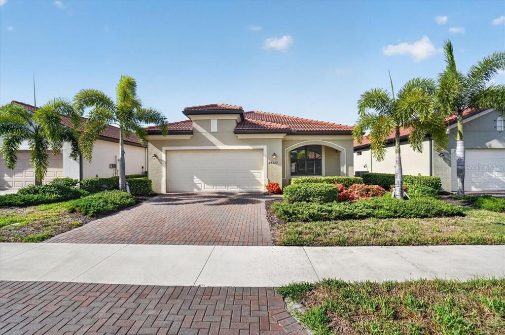 A single-story house with a tile roof, a two-car garage, and palm trees in front — 24229 SPARTINA DRIVE, VENICE, FL
