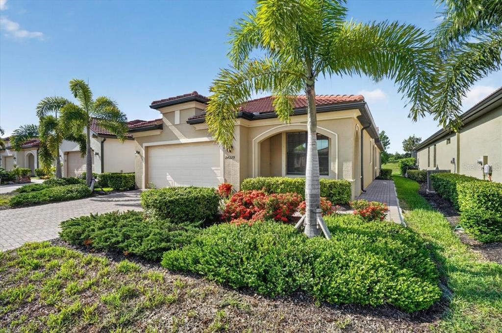 A single-story stucco house with a tile roof, two-car garage, and landscaped front yard — 24229 SPARTINA DRIVE, VENICE, FL