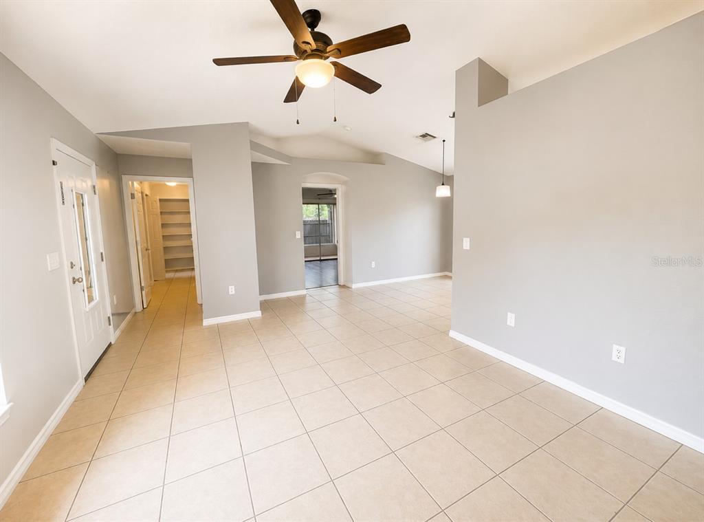 An open-concept living area features light gray walls, beige tile flooring, and a ceiling fan — 6108 PECAN COURSE, OCALA, FL