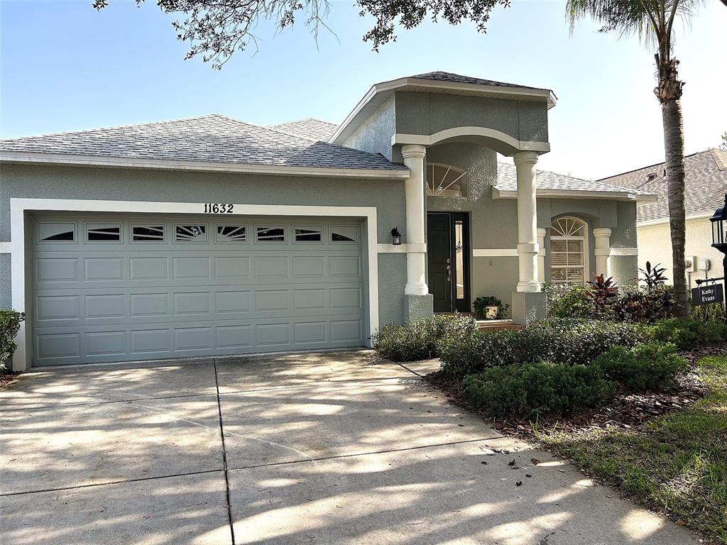 A single-story house with a gray garage, white columns, and a concrete driveway — 11632 HERITAGE POINT DRIVE, HUDSON, FL