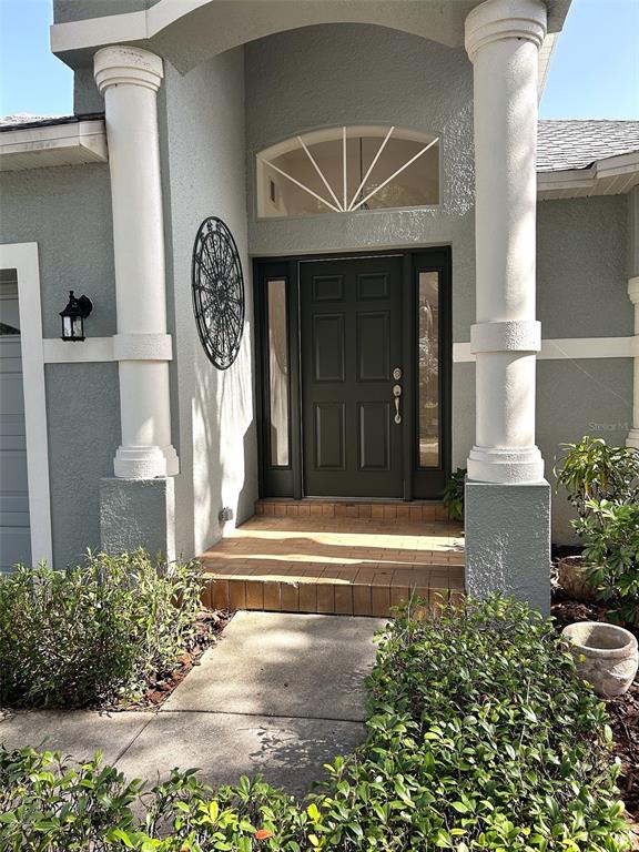 The front entrance features a dark door with sidelights, columns, and a semicircular transom window — 11632 HERITAGE POINT DRIVE, HUDSON, FL