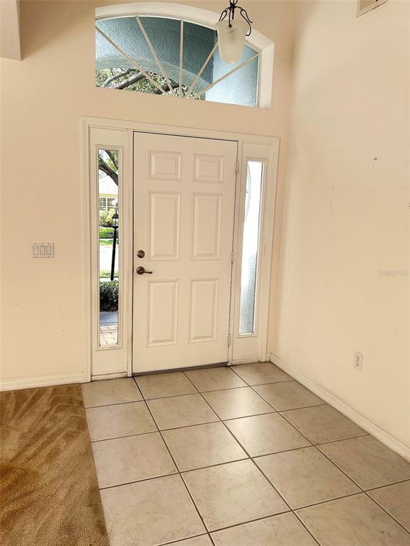 An entryway features a white front door with sidelights, a transom window, and tiled flooring — 11632 HERITAGE POINT DRIVE, HUDSON, FL