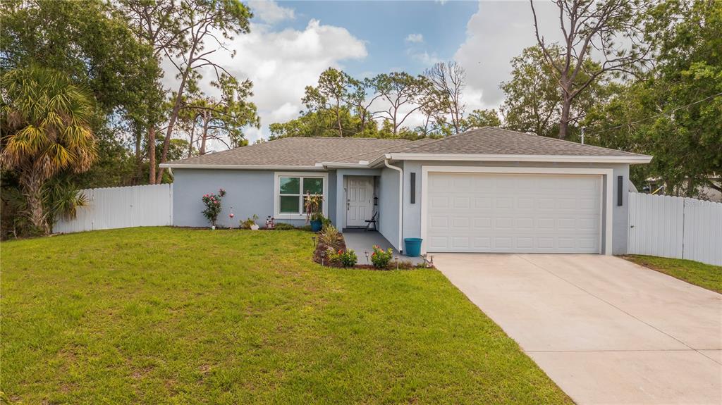 A single-story house with a light blue exterior, a two-car garage, and a white fence — 7081 BRAZIL CIRCLE, LABELLE, FL