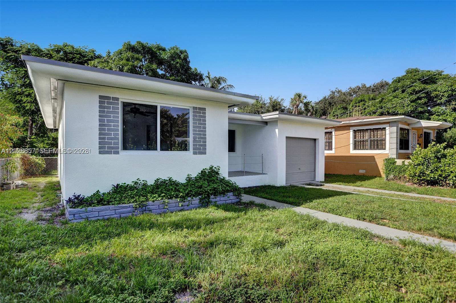 A white single-story house with a gray garage and a small front garden — 236 NW 42nd St, Miami FL 33127, MIAMI, FL