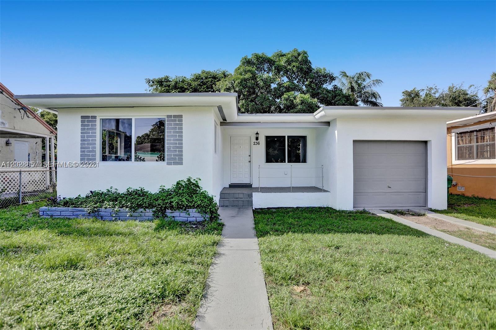 A single-story white house with a gray garage door and a front walkway — 236 NW 42nd St, Miami FL 33127, MIAMI, FL