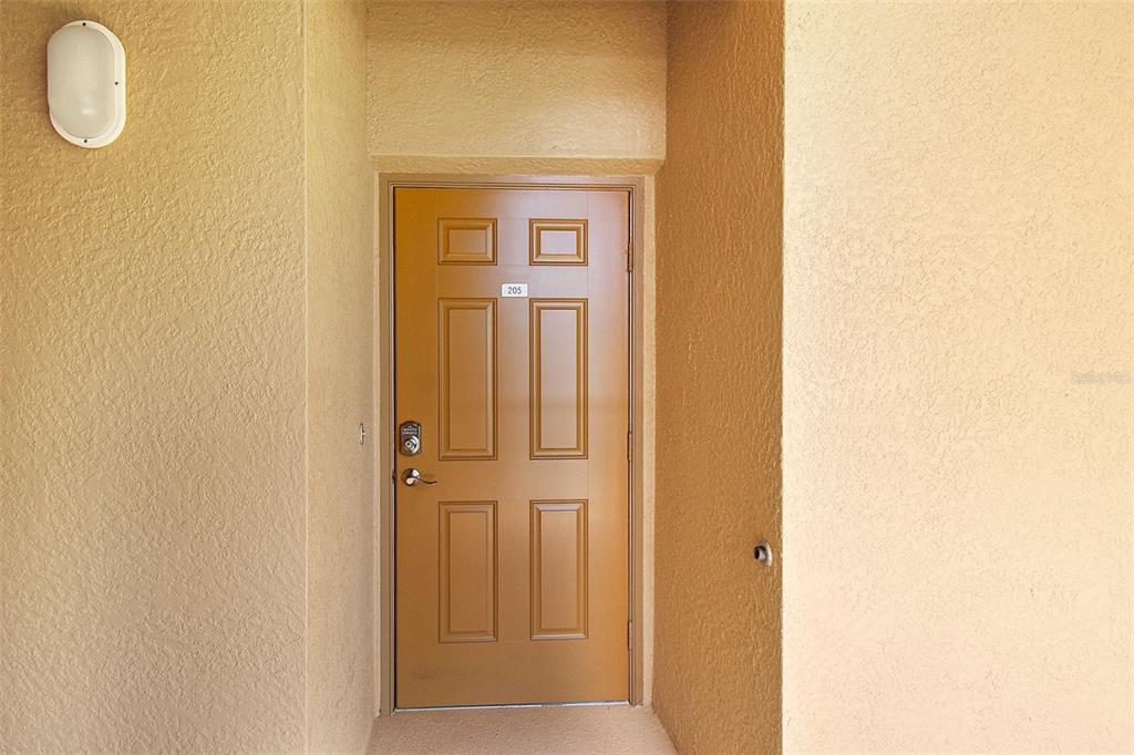 A tan exterior door with six panels and the number 205 is set in a wall — 8403 GRAND ESTUARY TRAIL UNIT 205, BRADENTON, FL