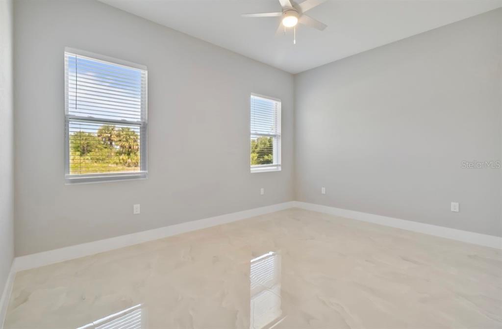 An empty room features light gray walls, white trim, tile flooring, and two windows — 20462 KENILWORTH BOULEVARD, PORT CHARLOTTE, FL