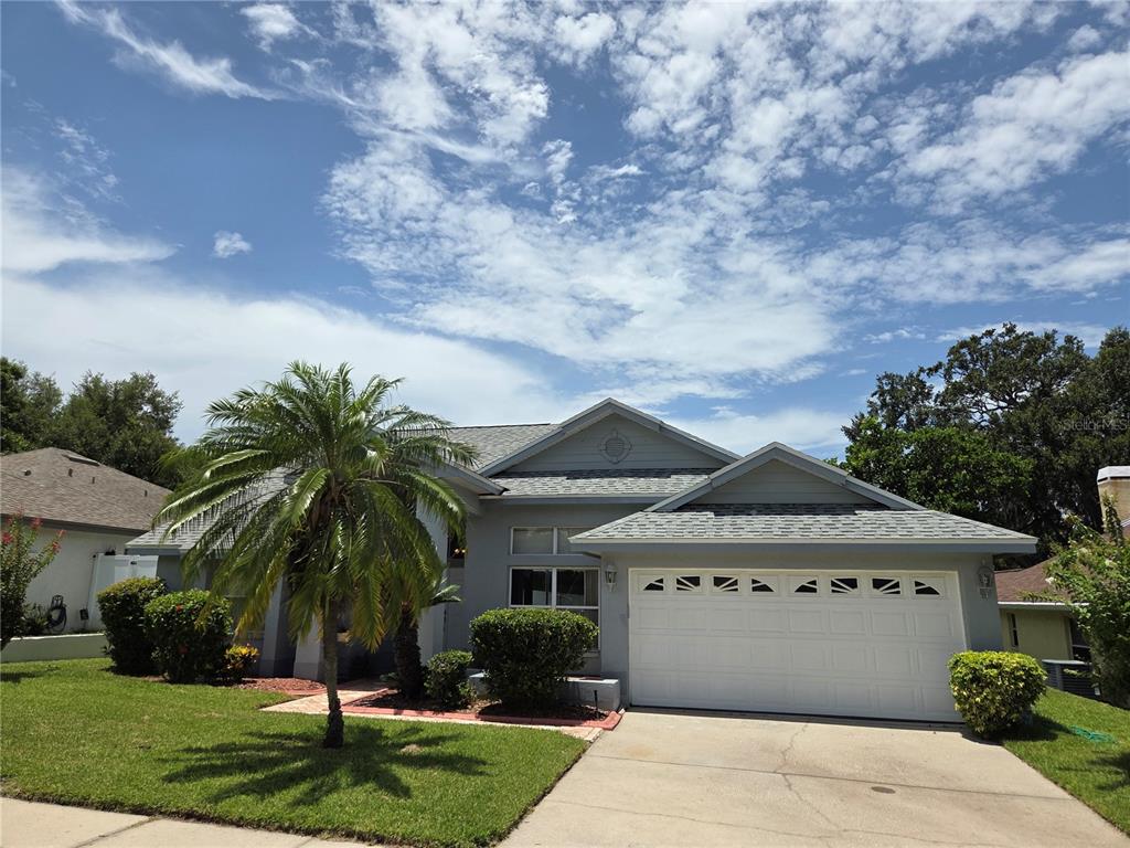 A single-story gray house with a white garage door and a palm tree in front — 770 WILDFLOWER DRIVE, PALM HARBOR, FL