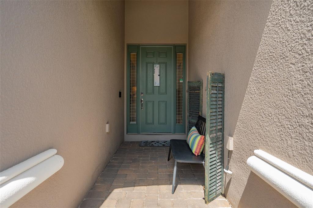 A covered entryway features a green front door, a small bench, and paver flooring — 1192 ESPERANZA RIDGE ROAD, CLERMONT, FL