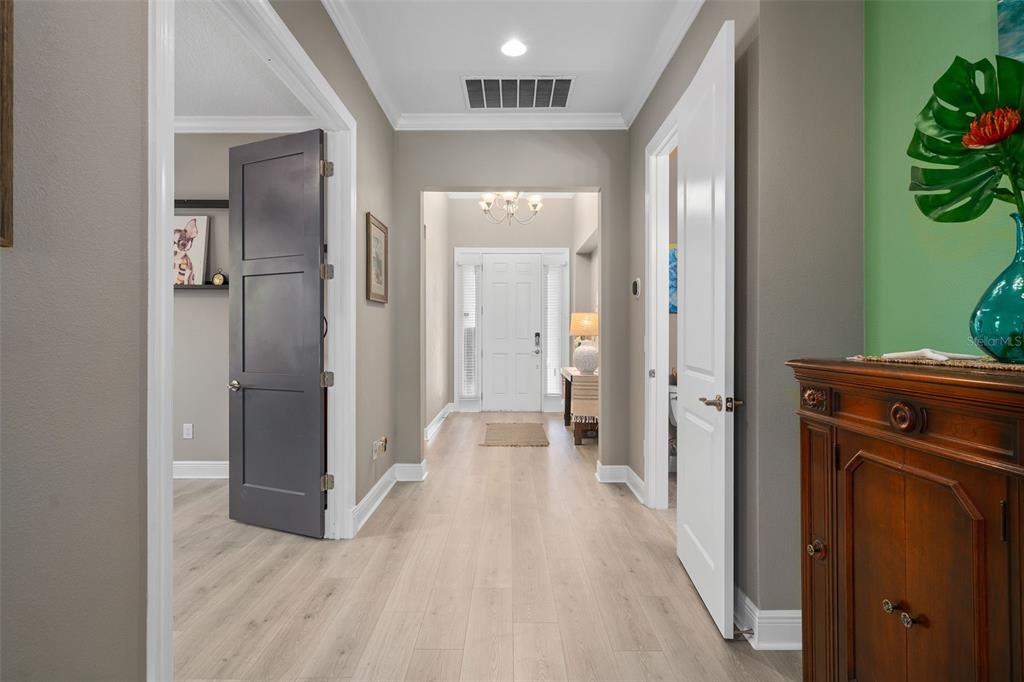A hallway with light wood flooring leads to a white front door with sidelights — 1192 ESPERANZA RIDGE ROAD, CLERMONT, FL