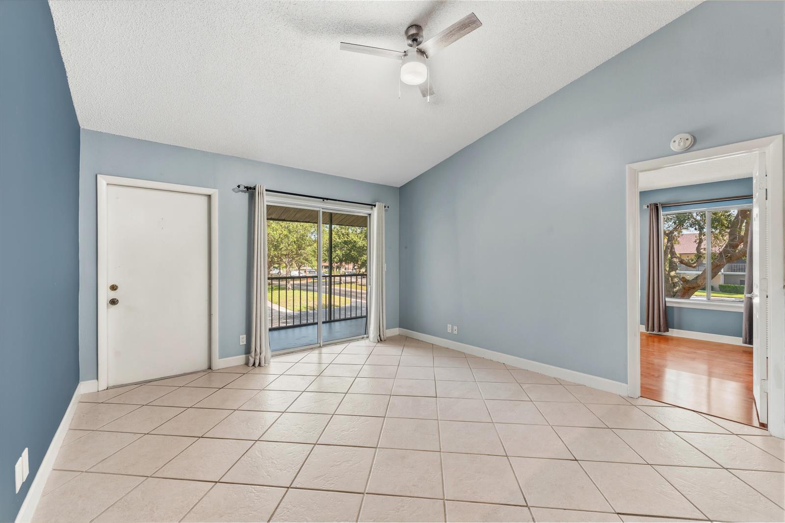 An empty room with light blue walls, tile flooring, a ceiling fan, and a balcony door — 6314 Chasewood Drive, Jupiter FL 33458, JUPITER, FL