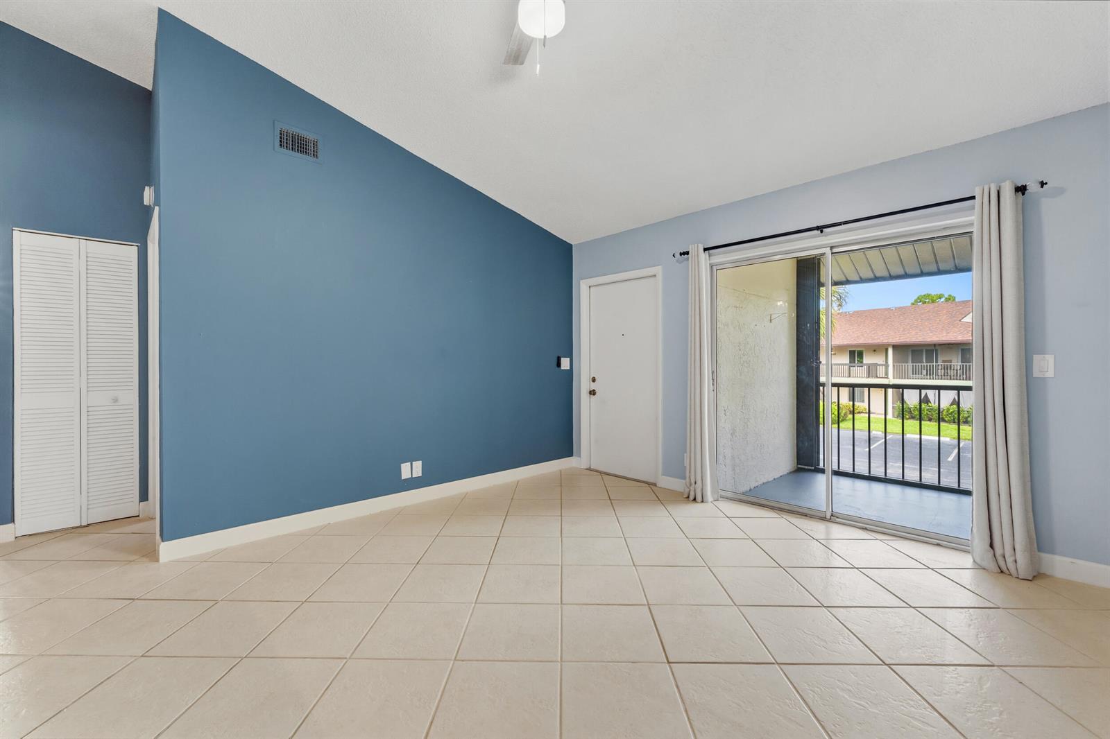 A room with blue accent walls, tile flooring, a ceiling fan, and a sliding glass door — 6314 Chasewood Drive, Jupiter FL 33458, JUPITER, FL