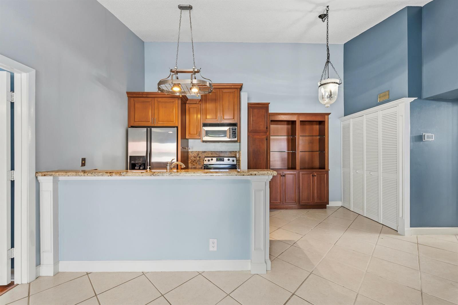 A kitchen features wood cabinets, granite countertops, stainless steel appliances, and a breakfast bar — 6314 Chasewood Drive, Jupiter FL 33458, JUPITER, FL