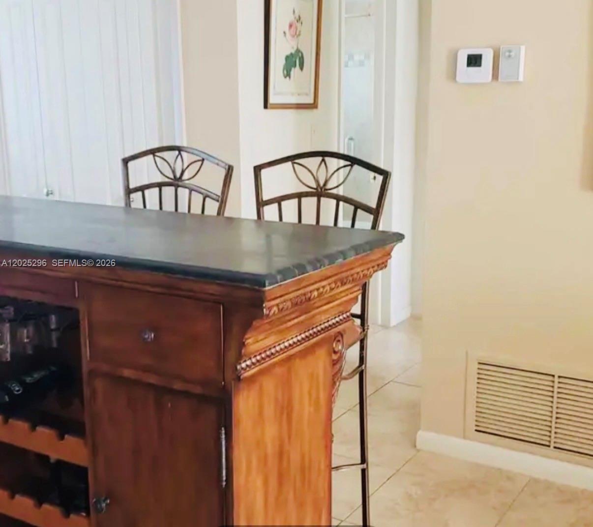 A kitchen island with a dark countertop and wooden base sits before two metal chairs — 251 S Golf Blvd # 289, Pompano Beach FL 33064, POMPANO BEACH, FL
