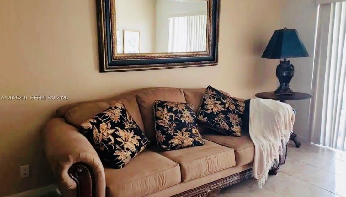 A tan sofa with patterned throw pillows sits beneath a large mirror in a room — 251 S Golf Blvd # 289, Pompano Beach FL 33064, POMPANO BEACH, FL