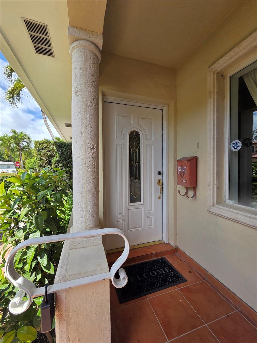 A white front door with a decorative glass insert sits on a tiled porch — 345 Malaga Ave, Coral Gables FL 33134, CORAL GABLES, FL
