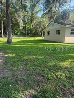 A view of a grassy backyard with a chain-link fence and the side of a house — 3115 SE 11TH STREET, OCALA, FL