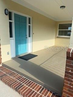 A covered front porch features a teal door, brick steps, and a light-colored exterior wall — 3115 SE 11TH STREET, OCALA, FL