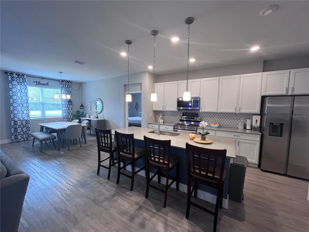 A modern kitchen features white cabinets, a central island with bar seating, and an adjacent dining area — 41 WHITE STAR DRIVE, PALM COAST, FL