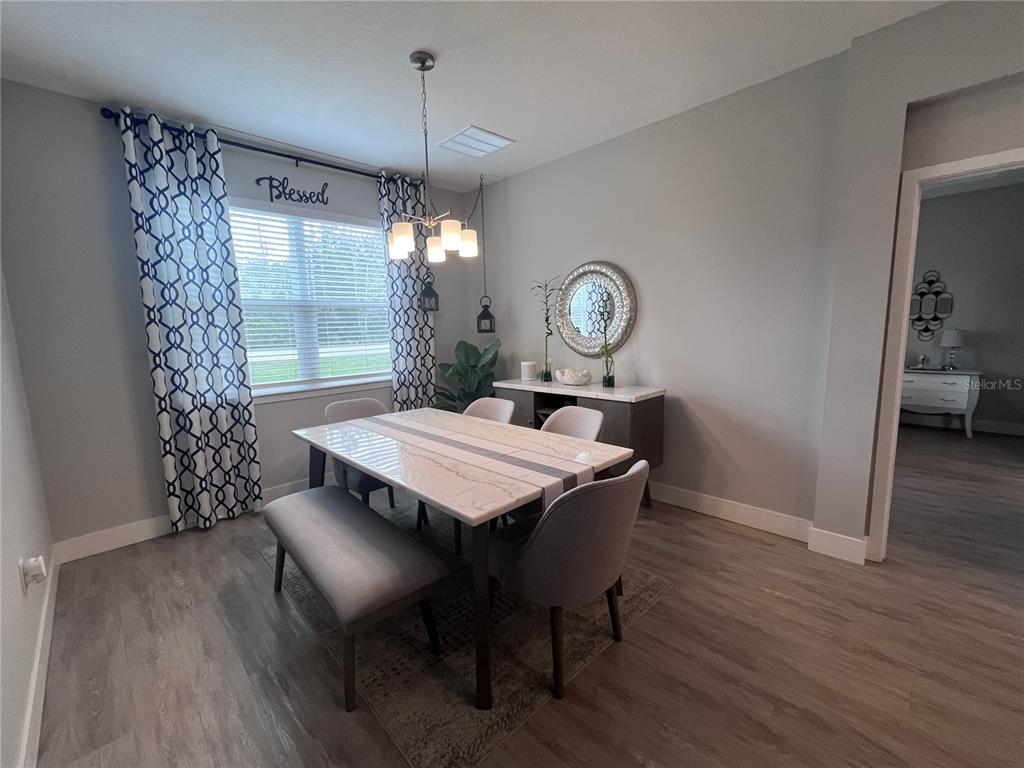 A dining room features a marble-topped table, gray upholstered chairs, a bench, and patterned curtains — 41 WHITE STAR DRIVE, PALM COAST, FL