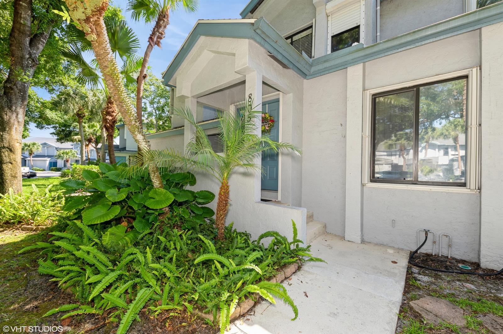 The exterior of a light-colored house features a covered entryway, a front door, and landscaping — 805 Harbour Pointe Way, FL 33413, FL